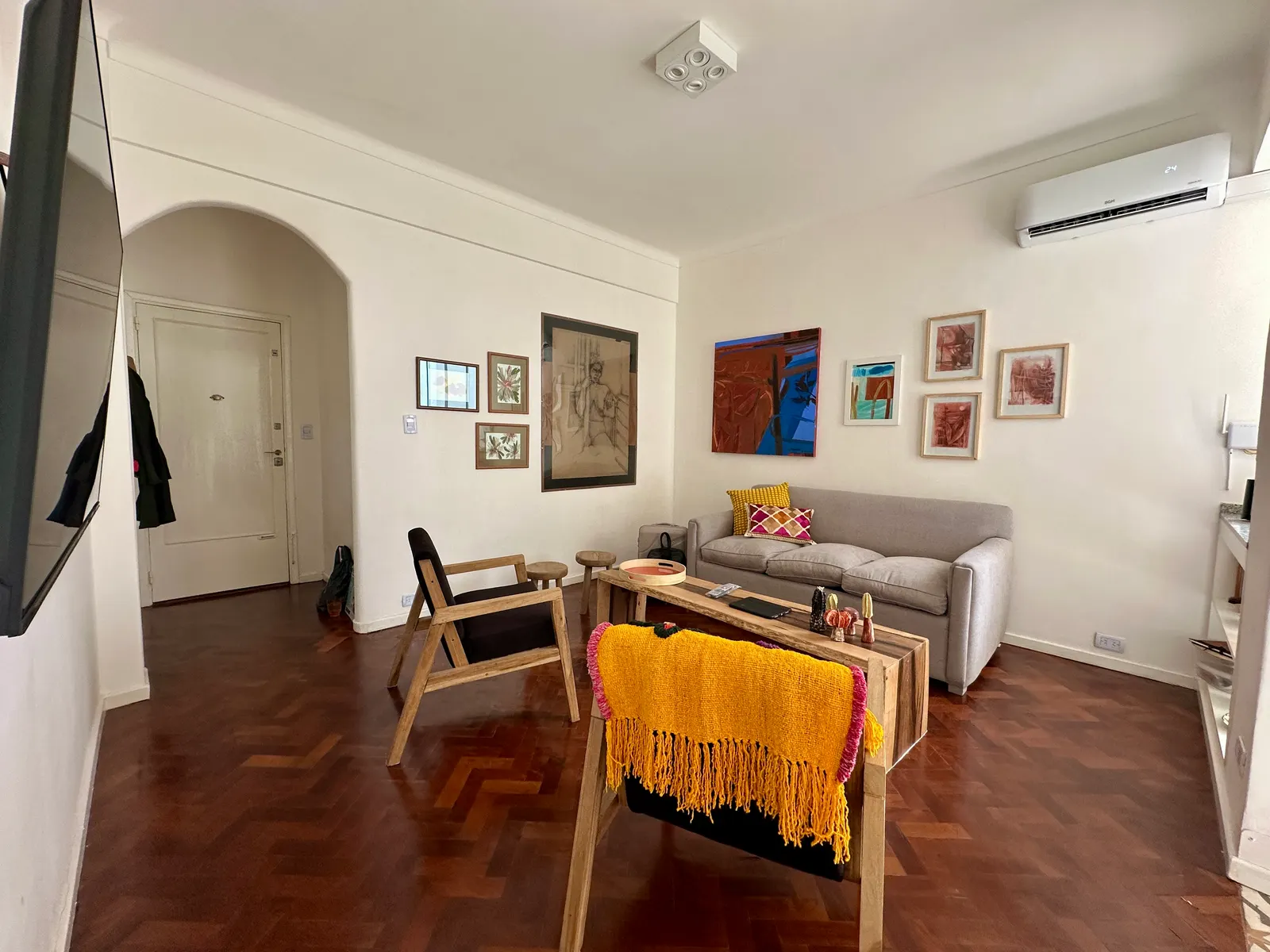 Living del departamento de Junín y French con piso de parquet, sofá y obras de arte en las paredes